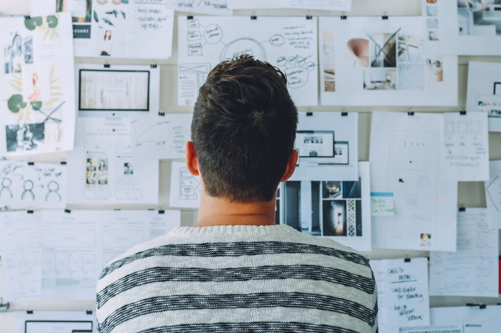 Man looking at a collection of papers on a board. Image by Pexels from Pixabay