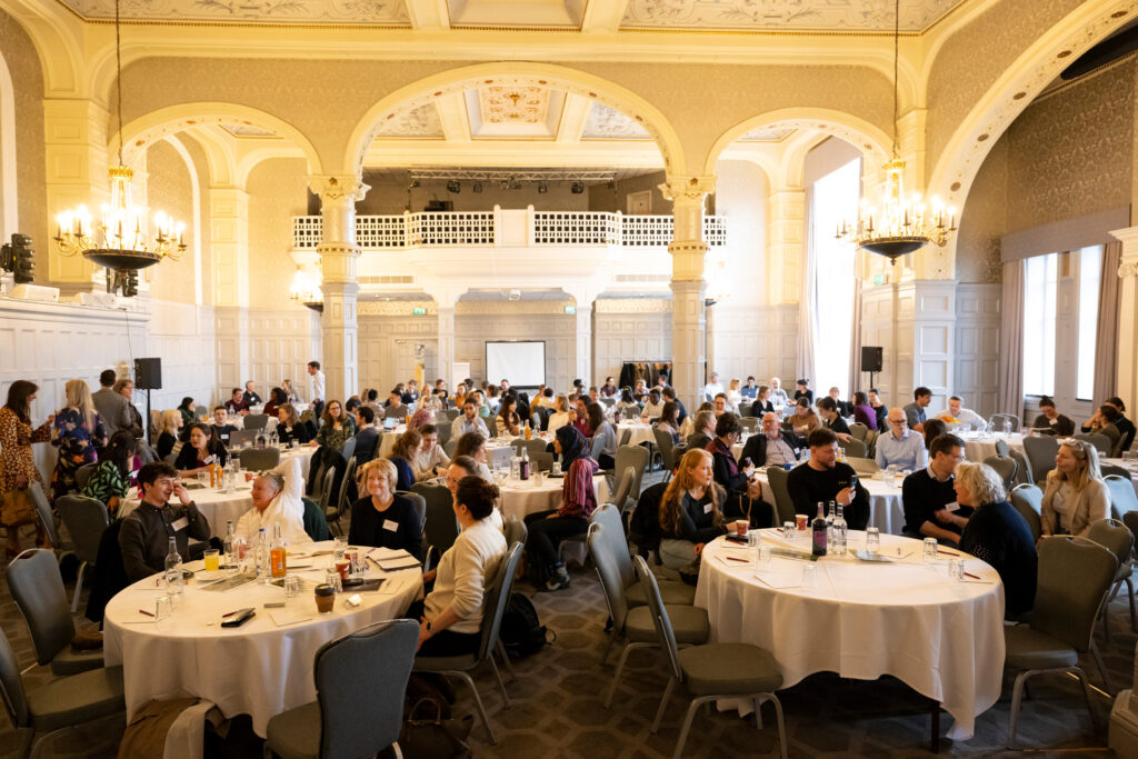 image shows members of the afn network gathered round tables in a confrence hall at big tent event