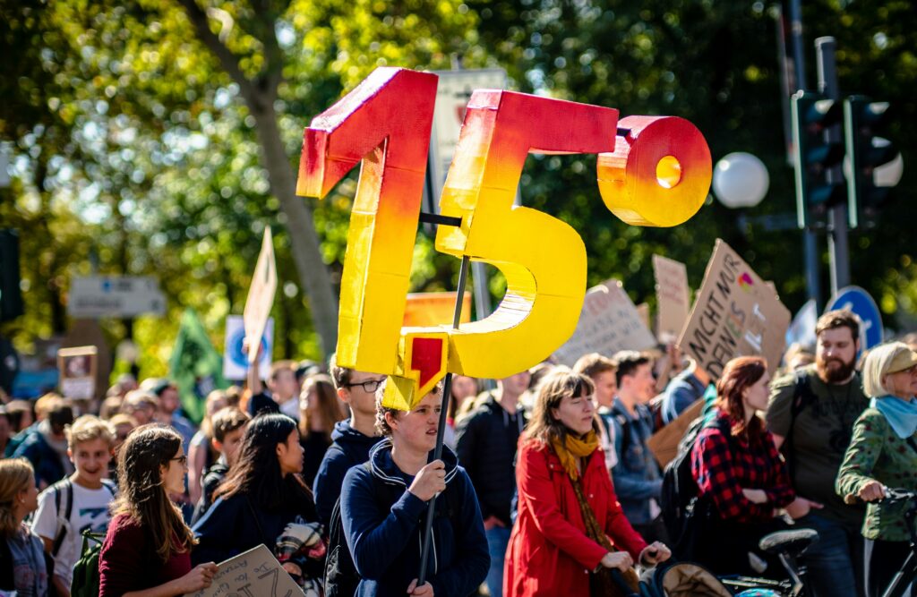 Balloons reading 1.5 degrees, floating above a crowd at a demonstration.