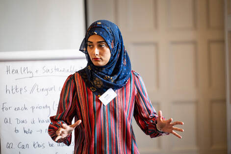 Saher Hasnain making a point in front of a flipchart at the Big Tent. The flipchard is headed "Healthy and Sustainable?"